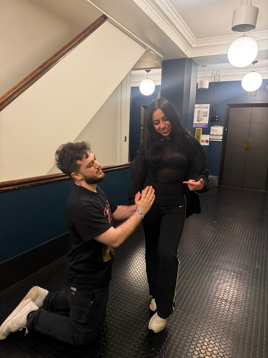 Michalis kneeling for Cristal in the Montier Tower hallway